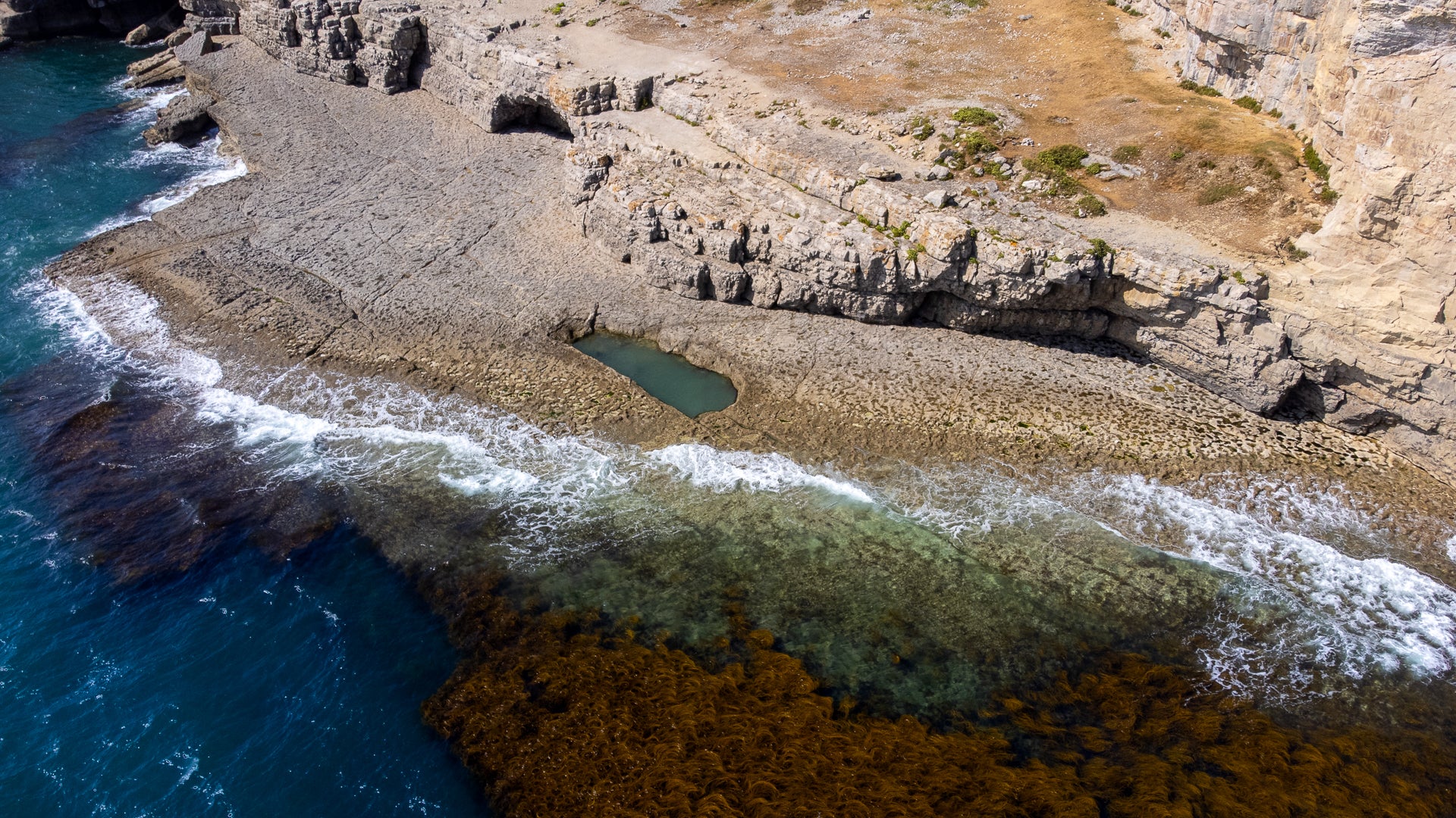 Aerial view of a rocky coastline with waves crashing against the shore.